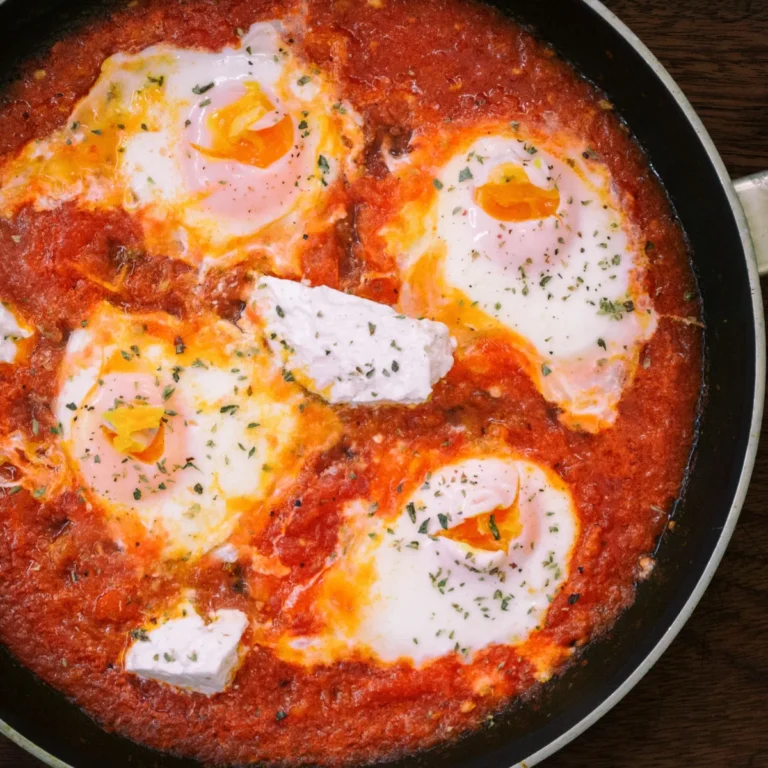 White fish fillets poaching in a red tomato and pepper sauce