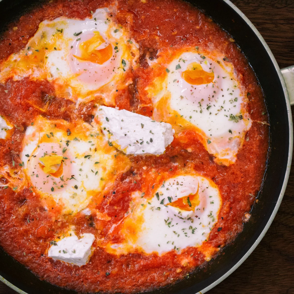 White fish fillets poaching in a red tomato and pepper sauce