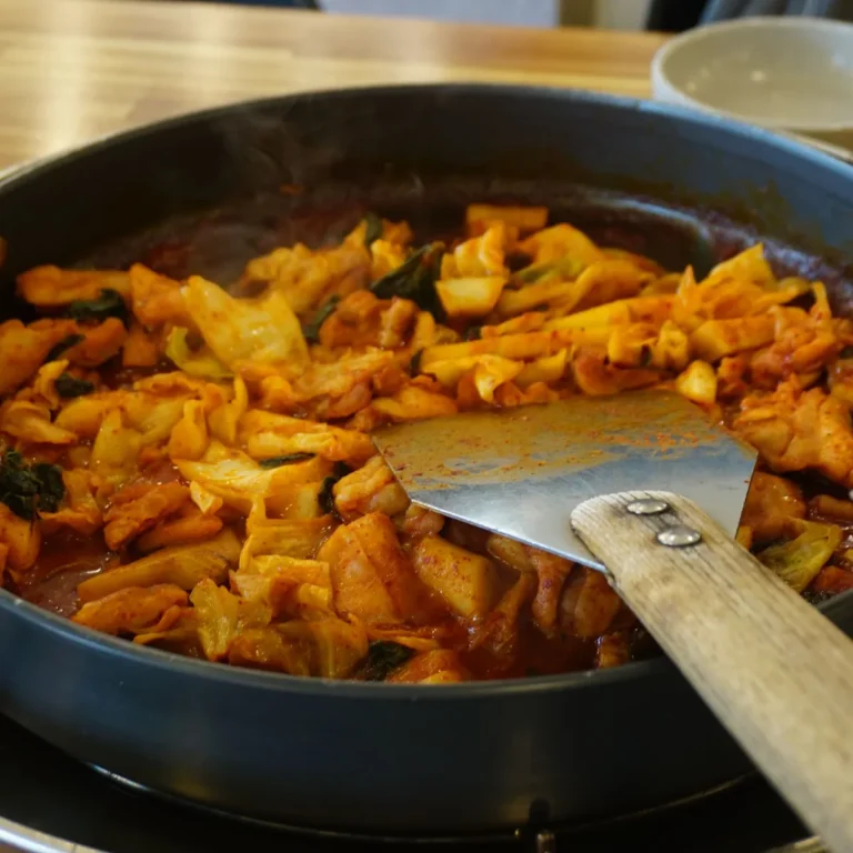 Stir fried chicken and charred cabbage with scallions in a dark pan
