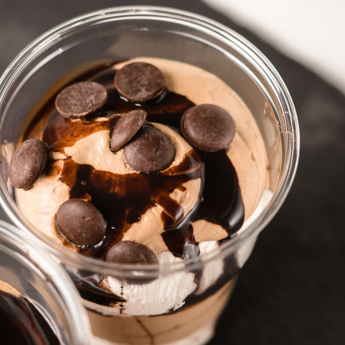 A small glass of dark chocolate peanut butter mousse topped with a swirl of peanut butter