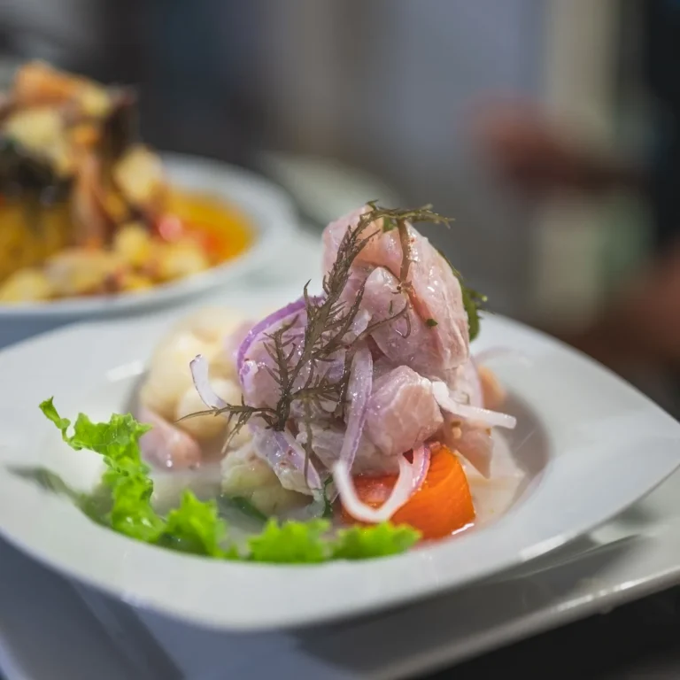 A plate of ceviche with cubes of white fish, red onion and fresh garnishes